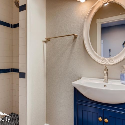- bold navy vanity with gold hardware and white framed mirror adds vintage inspired elegance
- step in tiled shower features classic dark blue accents for contrast
- neutral walls, simple lighting, and sleek finishes complete the clean look