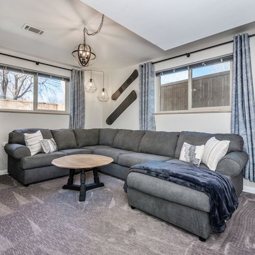 - spacious second living area with oversized gray sectional and two large windows
- perfect for movie nights casual hangouts or curling up with a good book
- soft carpet modern lighting and throw pillows create a cozy welcoming vibe