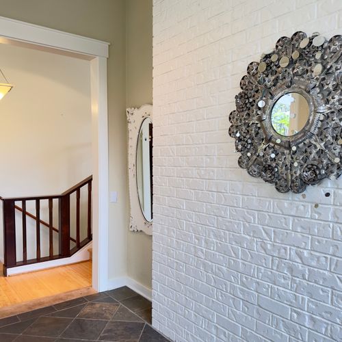 Step into a welcoming entry with a white brick accent wall, decorative mirror, and warm light. A calm first impression where you can drop your bags, take a breath, and ease into island time before heading upstairs or into the living space.