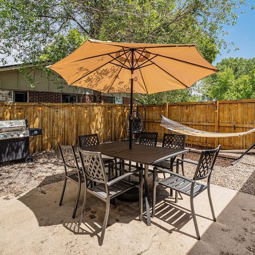 - dine outdoors under a large umbrella with seating for six and shady comfort
- propane grill sits nearby perfect for weekend barbecues or easy dinners
- surrounded by trees and fencing this cozy space feels private and relaxed