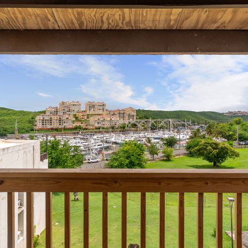 Wake up to this breathtaking view from your balcony, showcasing a sprawling marina bordered by lush green hills and modern architecture.