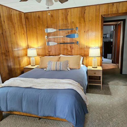 Bedroom #1:  features a queen-size bed, dresser, nightstand, lamp, ceiling fan, mirror, and desk.