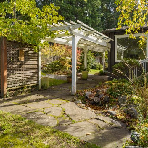 Follow the garden path beneath the pergola and feel the pace slow. This quiet walkway connects the home to peaceful outdoor spaces, framed by greenery, dappled light, and the calm of nature all around.