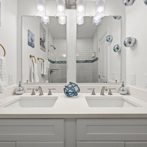 Enjoy a clean, modern bathroom with double vanities and bright white accents.