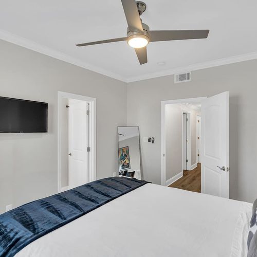 Airy bedroom w/ a wall-mounted TV & clean, minimal décor.