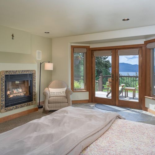 Master bedroom with a king bed, fireplace and doors opening to the decks outside.