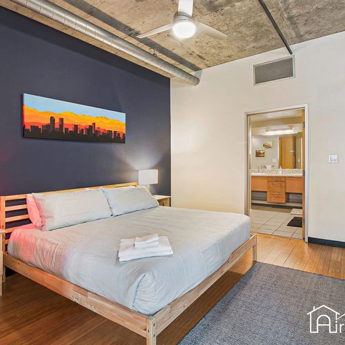 - rest easy in a minimalist bedroom with king bed, bold accent wall, and urban decor
- soft wood flooring and natural textures add warmth to the industrial ceiling style
- ensuite access and sunset skyline art make the space feel personal and calm