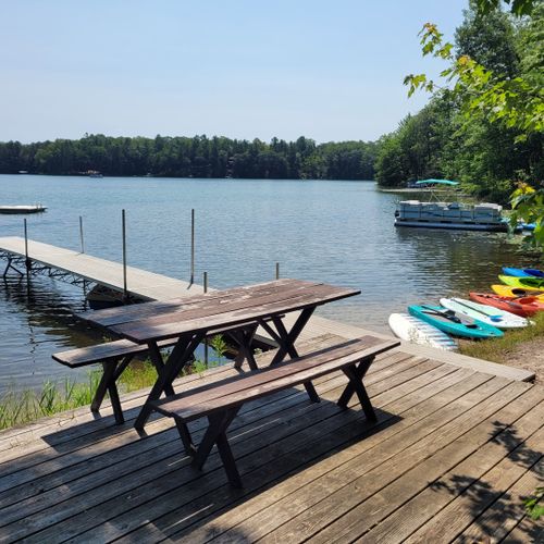 Exterior:  another view of the private lakefront showing the deck, picnic table, dock, swim raft, kayaks, and paddleboards.