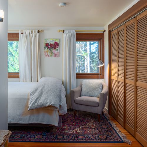 Queen bed with a reading chair and light, large closets with hangers.