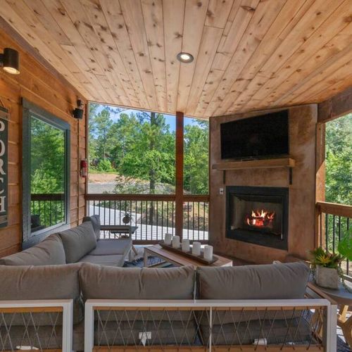 An oversized sectional placed around the outdoor fireplace and tv.