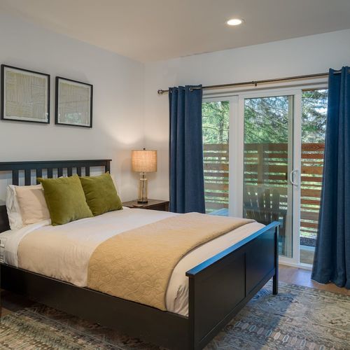Downstairs, the first bedroom features a queen-size bed, a generous closet, and access to the outdoor sitting area—perfect for relaxing.
