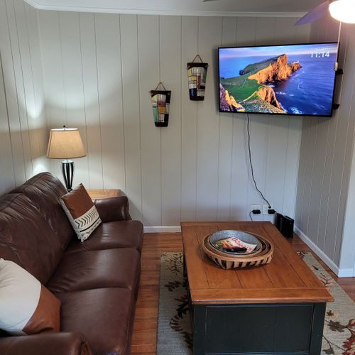 Living room:  comfy living room with a sofa, gas fireplace, live streaming television, coffee table, comfy chair, and ceiling fan.