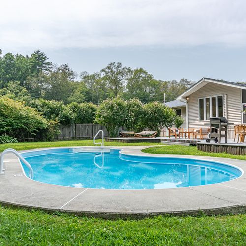 Private and fenced-in, with a tree-lined backdrop that creates a mesmerizing symphony on a windy day—perfect for relaxing on a float.