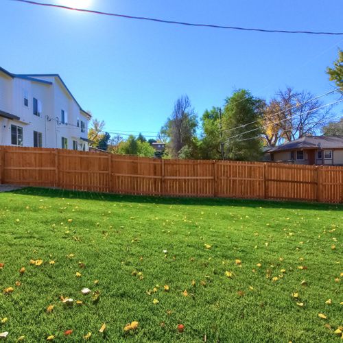 - view of the spacious fenced yard looking back toward the home and patio seating