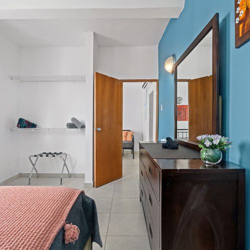 Experience tranquility in this bright and airy bedroom, complete with all the essentials for a restful stay. The pops of color add a touch of vibrancy, creating a welcoming and relaxing atmosphere.