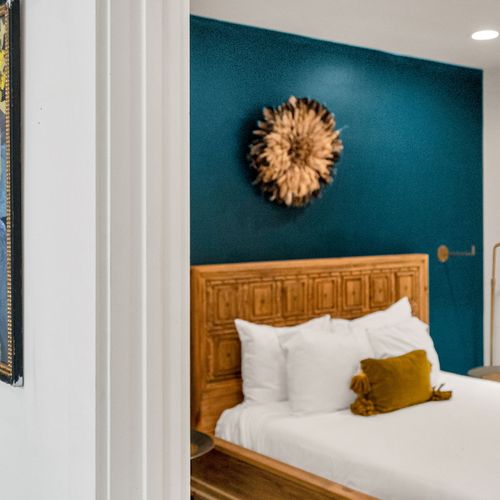Step into a cozy, modern bedroom with bold accent walls, warm wood touches, and inviting lighting—perfect for a restful night.