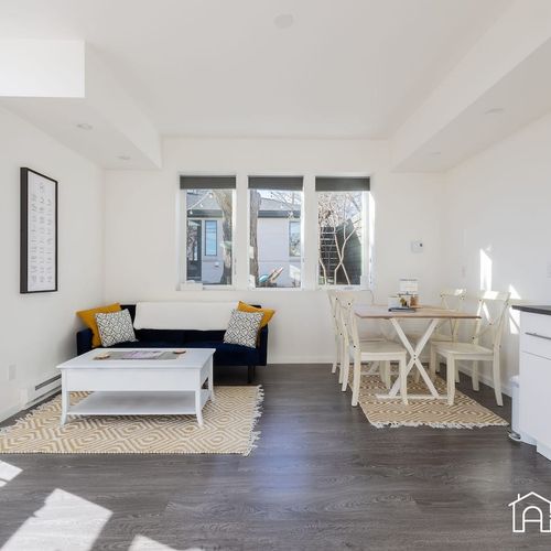 - soak up the sunlight in this airy living and dining space with leafy plant accents
- cozy navy sofa with cheerful pillows and patterned rugs bring warmth to the room
- gather at the dining table beside large windows that frame the outdoors beautifu