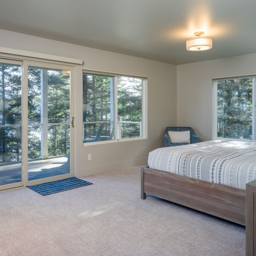 Lower Level Guest bedroom ensuite with a king bed, reading chair, and water views.