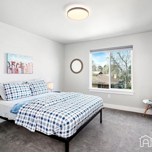 - cheerful bedroom with matching plaid bedding and playful art for a relaxed stay
- large window frames views of treetops and neighboring rooftops
- carpeted floors and soft touches provide extra comfort day and night
