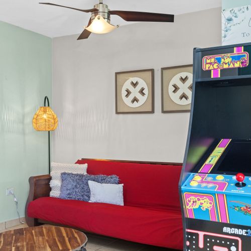 Charming living room with vibrant red sofa, unique decor, and retro gaming for a blend of comfort and fun.