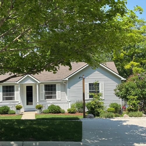 EXTERIOR:  A broader view of the front of the house showing the parking area.