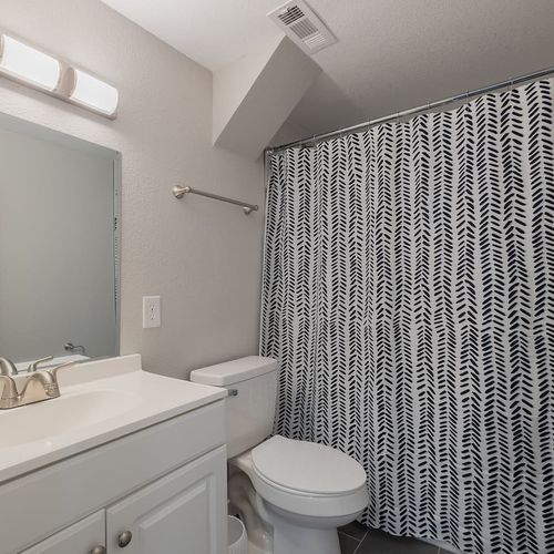 - compact bathroom with tub shower combo, patterned curtain, and crisp white vanity
- modern fixtures and clean finishes make this space feel fresh and functional
- great for guests staying in the lower level with everything you need close by