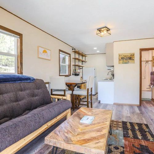 - relax on the cozy log frame futon in a bright, welcoming living space
- dine at the pub style table near the kitchen with rustic open shelving
- easy access to bathroom and bedrooms adds to the cabin’s functional layout