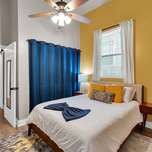 Cozy bedroom w/ warm mustard & blue tones & soft, layered bedding.