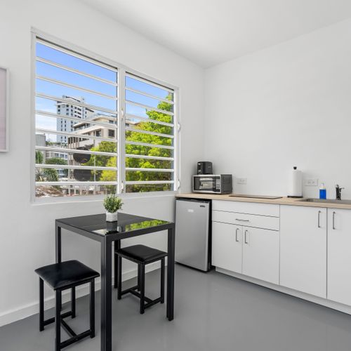 A sleek, white kitchenette complements the minimalist design, offering guests both style and functionality during their stay.