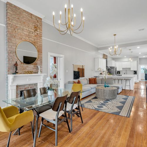 Elegant living and dining space featuring exposed brick, a cozy fireplace, and modern decor.