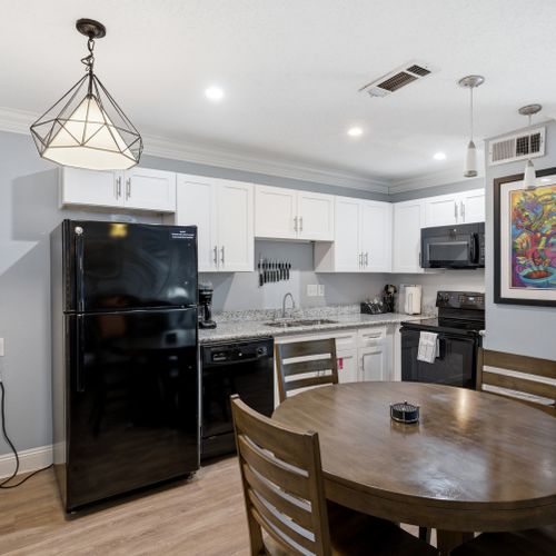 Bright kitchen w/ white cabinetry, black appliances & generous counter space.
