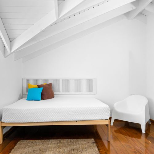 Relax in a bright and airy main room with cozy bed and calming all-white decor – perfect for restful nights.