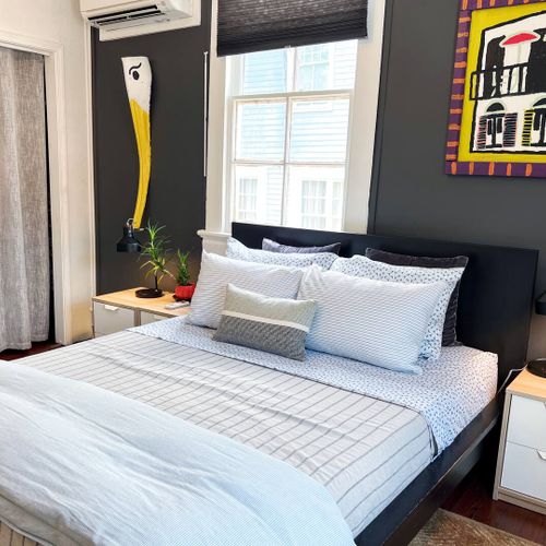 Sun-drenched bedroom w/ a bed & natural light pouring through the windows.