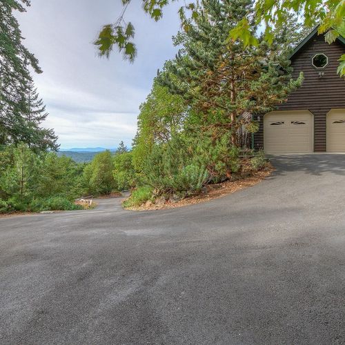 Paved driveway and parking at the top for three cars.  There is extra parking down by the lower garage.