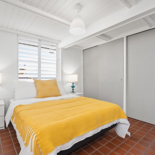 Bright, airy bedroom with a pop of color, offering comfort and style.