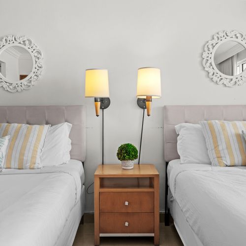 Thoughtfully designed bedroom with dual beds, each featuring cozy bedding and individual reading lamps