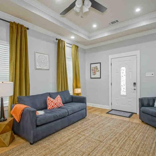 Sink into the plush sofa & catch up on your favorite shows in this welcoming living room w/ golden curtains.