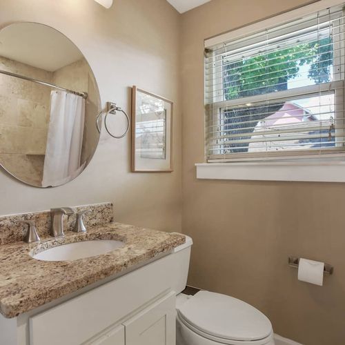 Freshen up in this bright and modern bathroom, featuring a sleek granite countertop and a spacious shower. With plenty of natural light and a clean design, it’s the perfect spot to start or end your day in comfort.