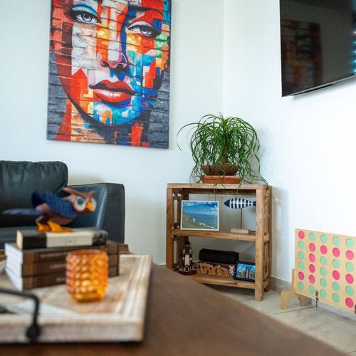 Discover a blend of modern art and comfort in this inviting lounge. Enjoy a striking wall piece, a convenient TV, and thoughtful decor that creates a unique and relaxing atmosphere.