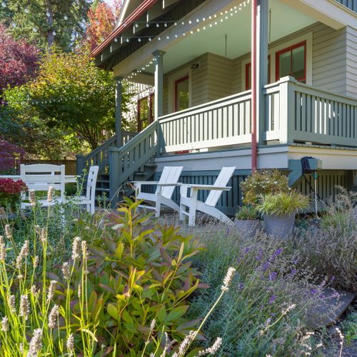 A beautifully landscaped outdoor patio with Adirondack chairs, perfect for unwinding under the trees.