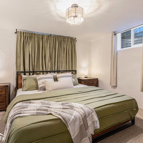 Enjoy spacious comfort in this inviting downstairs bedroom, featuring a king-size bed adorned with plush linens.