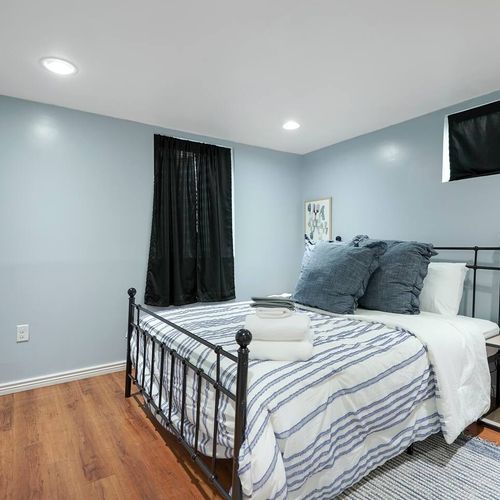 - peaceful and private basement bedroom with dark drapes for restful sleep
- iron bed frame and navy textiles add a bold touch to the soft blue palette
- plenty of space to stretch out and relax in this cool, calming retreat