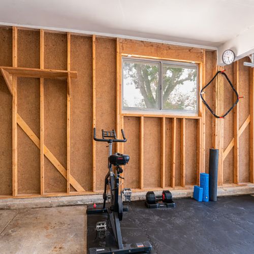 The garage is transformed into a versatile gym space, complete with essential equipment like a rower and punching bag, ideal for fitness enthusiasts to work out conveniently at home.