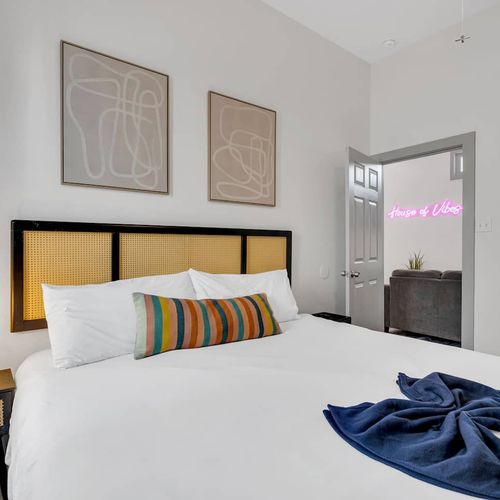Cozy bedroom w/ bold black-frame bed, neon accent, & teal curtains adding personality.