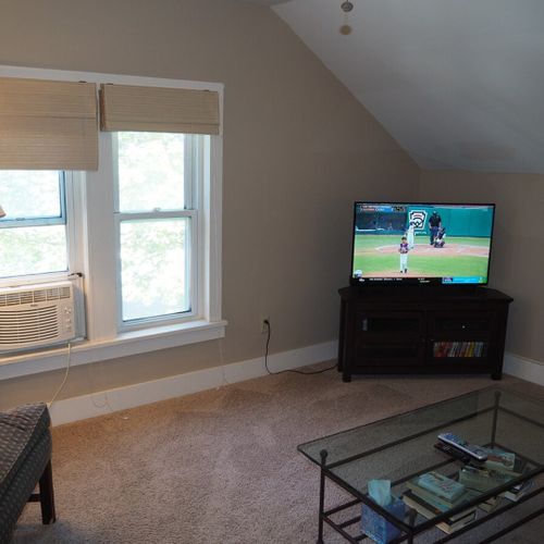 Overall:  the home has a comfy living room with a sofa, coffee table, chair, lamp, window a/c, and live streaming television.