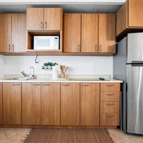 Cook your favorites in a kitchen with natural wooden cabinets, fridge, and all essentials provided.