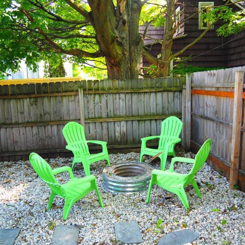 Exterior:  the fully fenced-in backyard with newly expanded deck, new hot tub, bonfire ring, propane grill, and picnic table with umbrella.