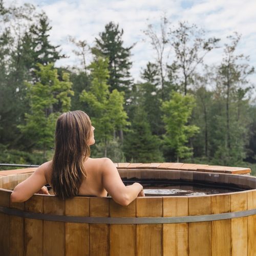 Hot tub centrally located between the pool house and the main house with views of the forest.