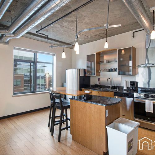 - bright and stylish kitchen with an island for morning coffee or casual meals
- pendant lights and exposed ductwork enhance the industrial chic design
- large window fills the space with natural light and city views
