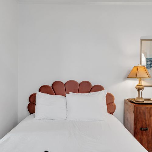 Bedroom w/ a bold statement headboard & warm, layered bedding.